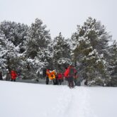 Groupe de randonneurs en raquette à travers la neige qui s'avancent vers une forêt