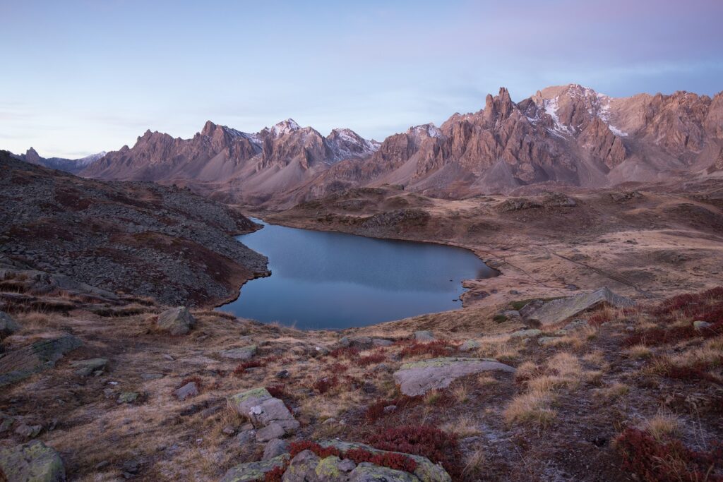 Paysage de montagne dans la vallée de l'Ubaye avec un ciel et une lumière rosée due au coucher ou lever du soleil, avec un lac en contrebas