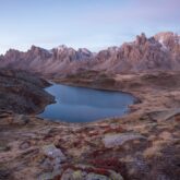Paysage de montagne dans la vallée de l'Ubaye avec un ciel et une lumière rosée due au coucher ou lever du soleil, avec un lac en contrebas