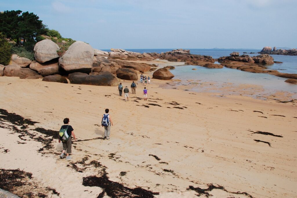 Groupe de randonneurs sur un sentier sur le sable sur la côte de granit rose en Bretagne