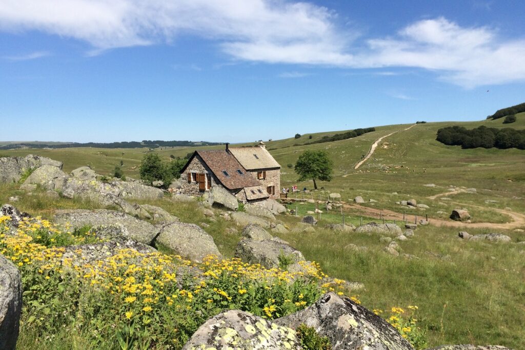 Paysage de montagne avec une maison en pierre au centre du paysage, encadré de sommets