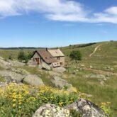 Paysage de montagne avec une maison en pierre au centre du paysage, encadré de sommets
