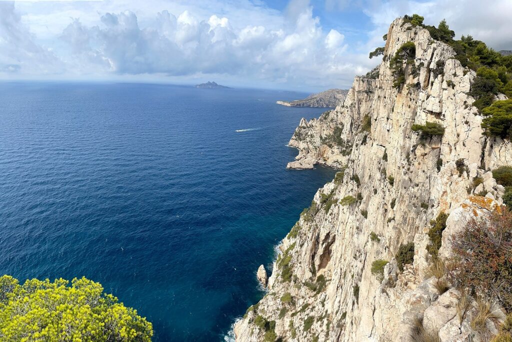 Paysage estival des calanques avec sur la droite des falaises et la mer aux couleurs bleu et bleu turquoise sur la droite