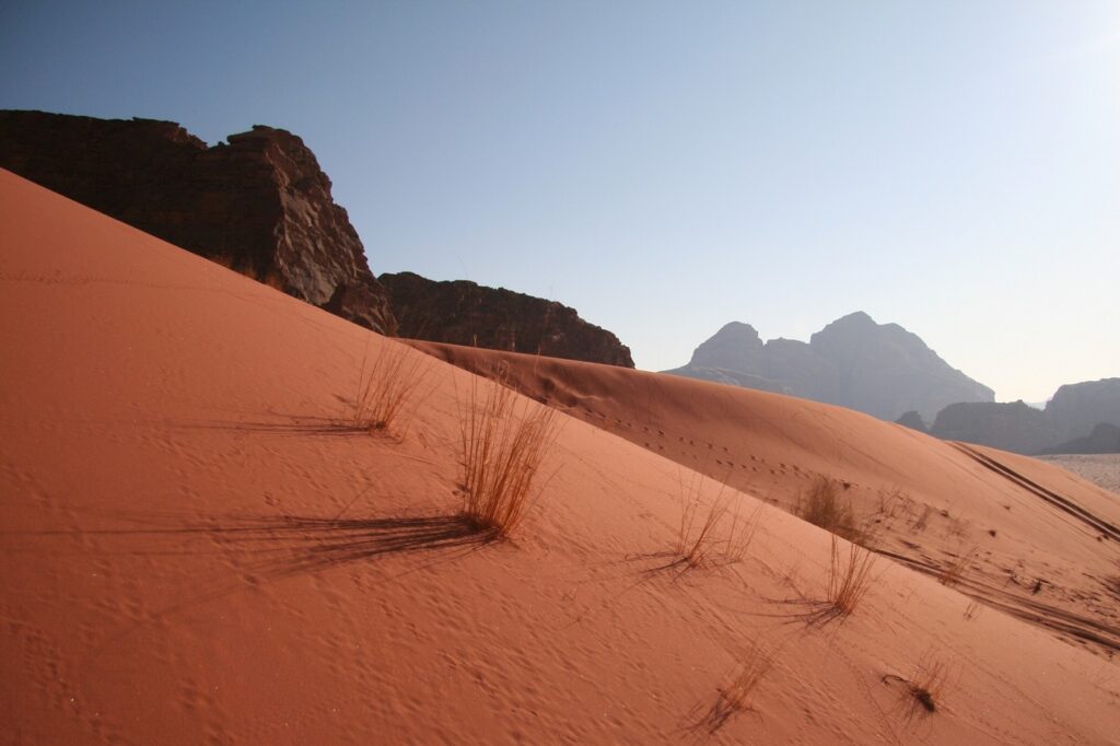 Paysage de la couleur rosée du sable au soleil, avec des sommets montagneux en fond