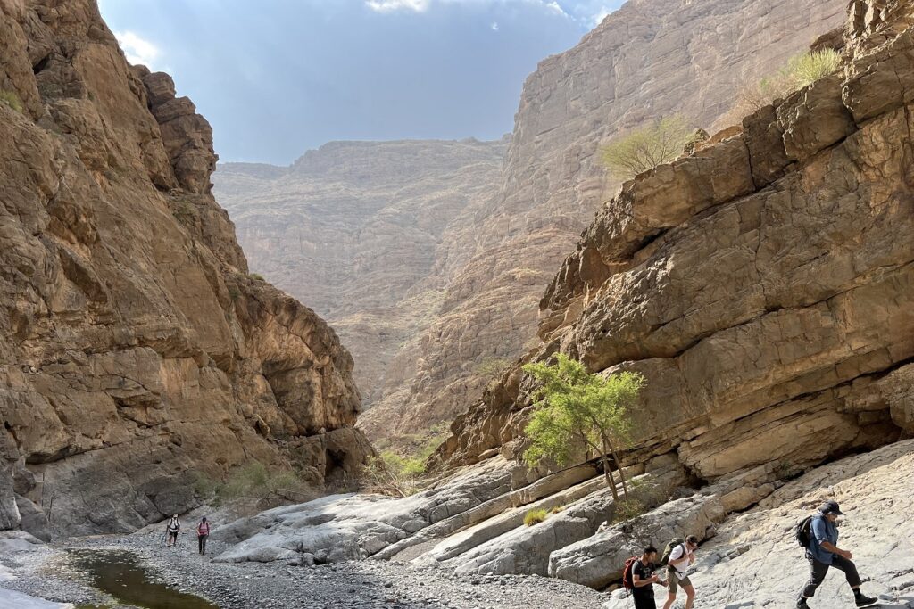 Groupe de randonneurs avec leur guide dans un canyon de roches à Oman.