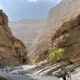 Groupe de randonneurs avec leur guide dans un canyon de roches à Oman.