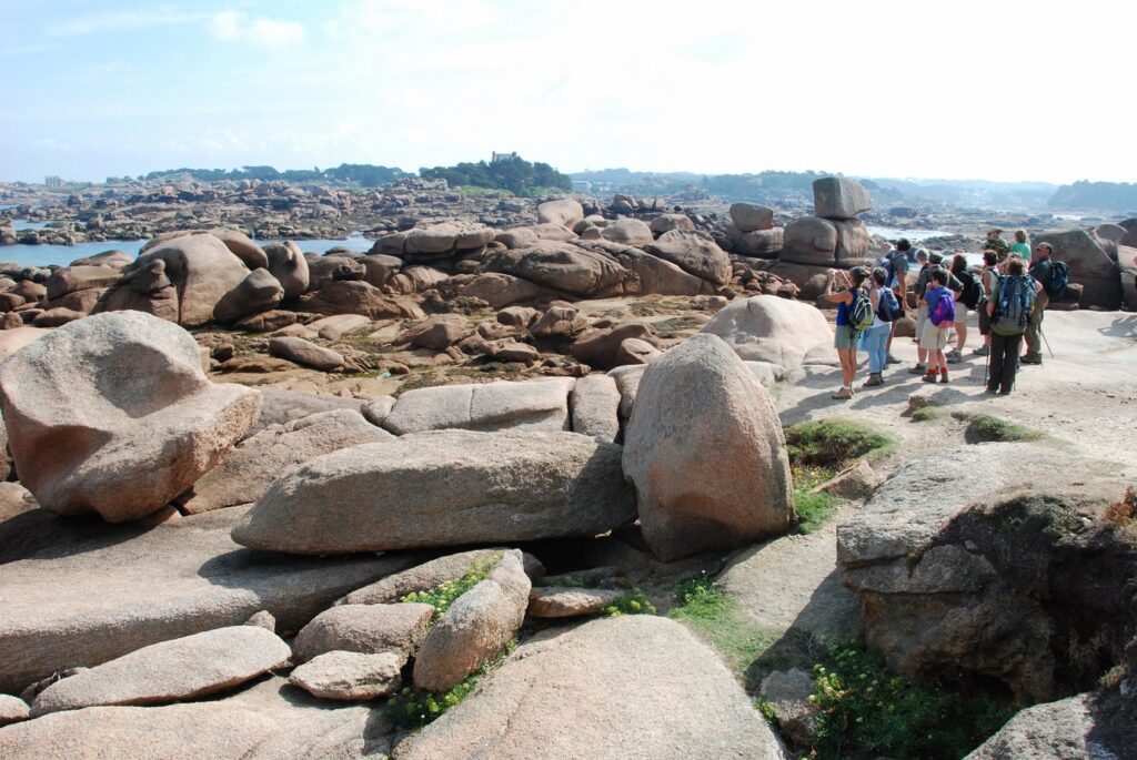 Groupe de randonneurs sur l'île de Bréhat en Bretagne avec leur guide sur un sentier de rochers