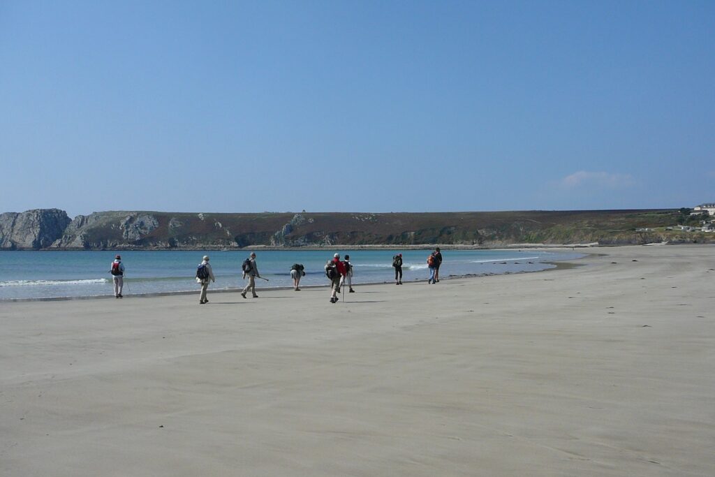 Groupe de randonneurs avec leur guide en train de marcher sur la plage au cours d'un séjour de randonnée sur la presqu'île d'Ouessant