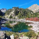 Paysage de montagne avec des sommets et un petit lac au pied de reliefs avec de la végétation diverse