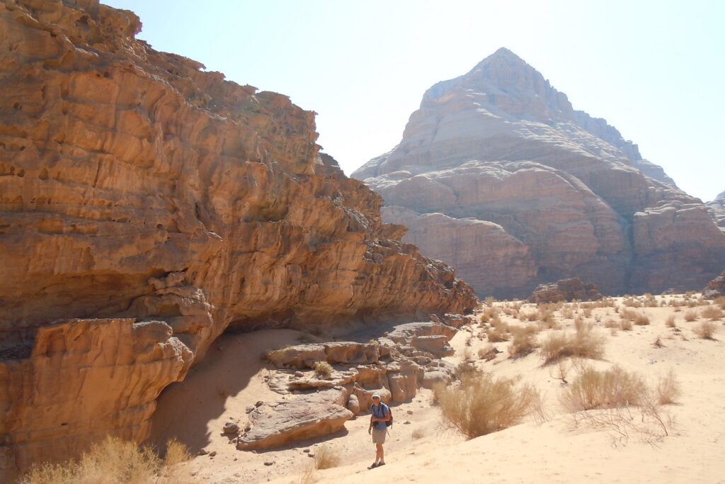 Randonneurs face à un sommet de pierre en Jordanie, le paysage est éclairé par un soleil intense