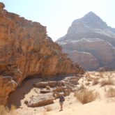 Randonneurs face à un sommet de pierre en Jordanie, le paysage est éclairé par un soleil intense