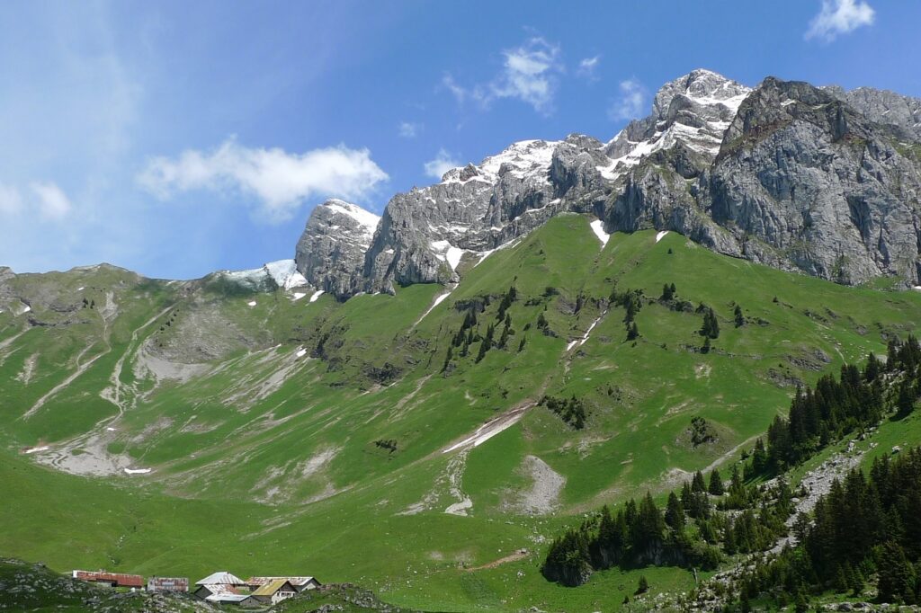 Paysage de montagne dans le massif du Chablais avec au loin des sommets enneigés malgré le soleil estival
