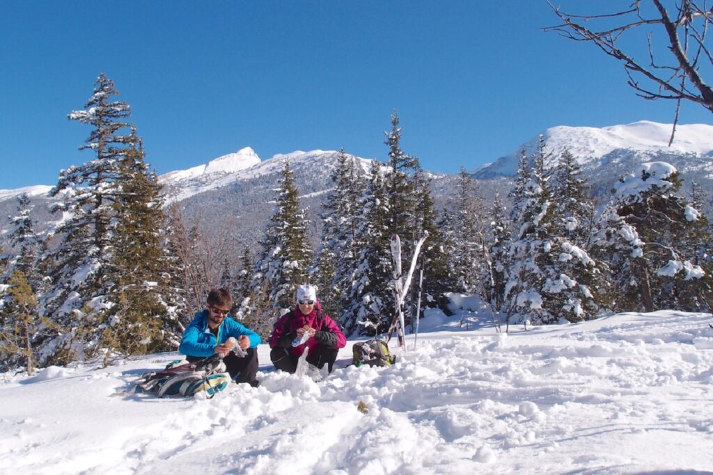 groupe de randonneurs qui prennent leur pique-nique dans la neige lors d'un séjour accompagné d'un guide de balades en ski de fond dans le Vercors