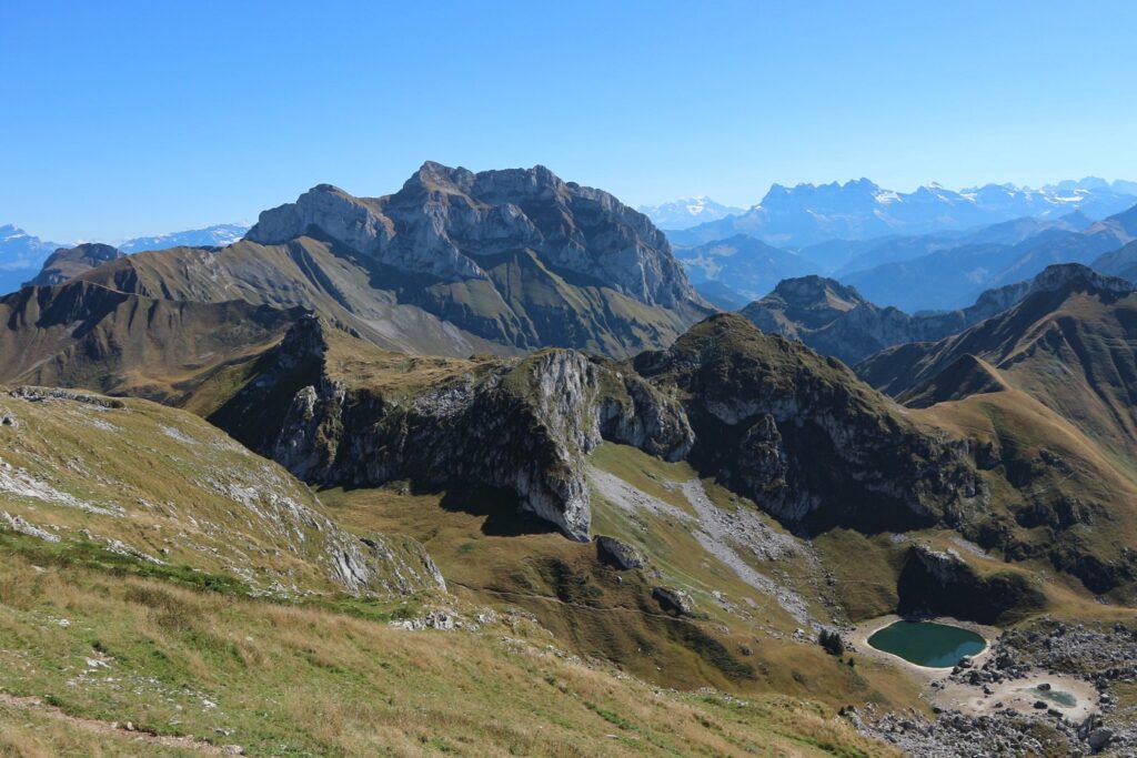 Paysage de montagne avec des sommets et des plaines verdoyantes sous un soleil estival