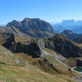 Paysage de montagne avec des sommets et des plaines verdoyantes sous un soleil estival