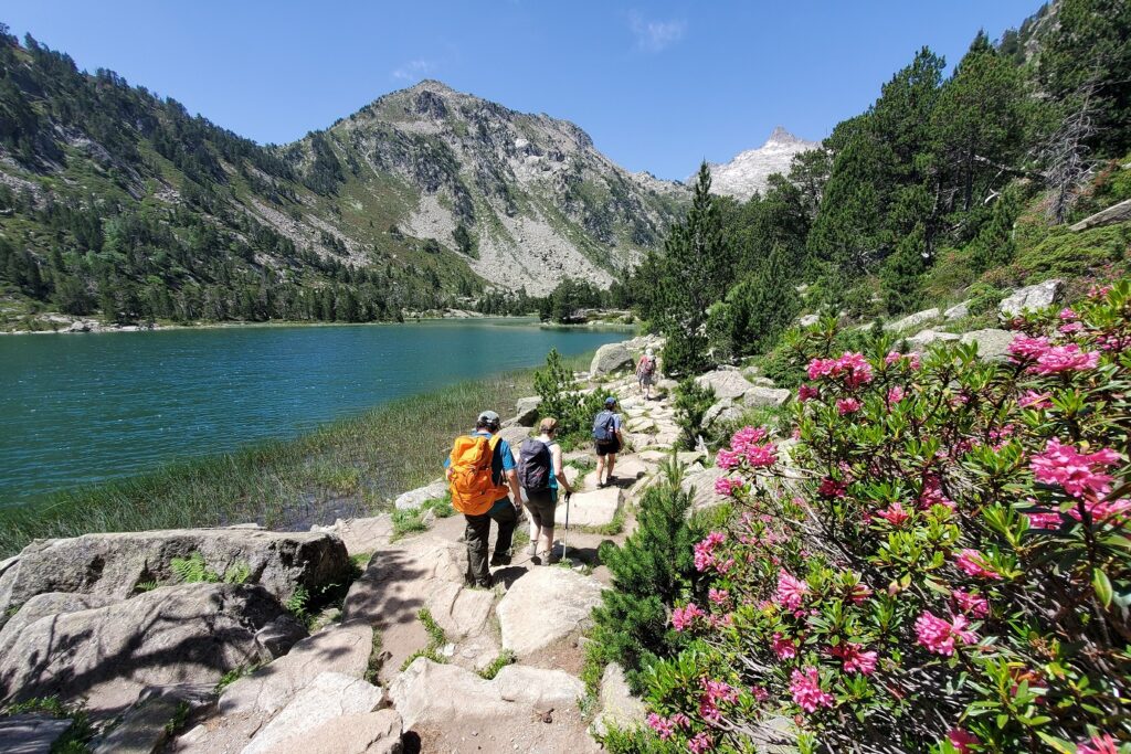 Groupe de randonneurs sur un sentier dans le massif du Néouvielle avec en fond des sommets