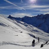 Paysage hivernal dans le Queyras avec un groupe de randonneurs sur un sentier en raquettes dans le massif du Queyras sous un grand soleil