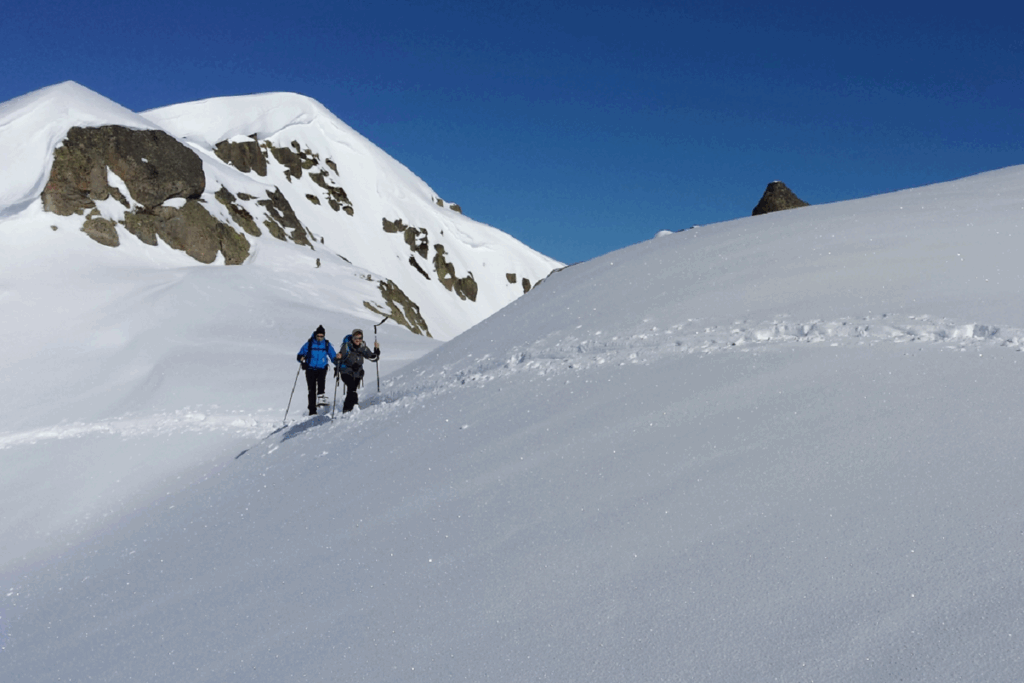 Groupe de randonneurs à flanc de montagne sur un sentier enneigé