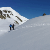 Groupe de randonneurs à flanc de montagne sur un sentier enneigé