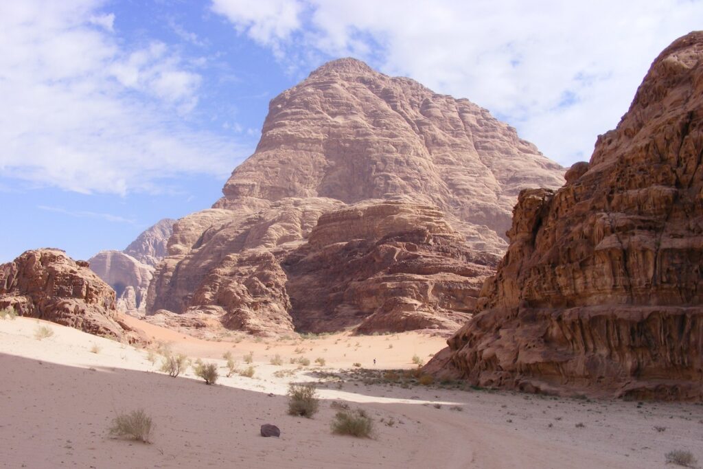 Paysage de Jordanie avec des sommets de pierre en fond et du sable blanc au premier plan