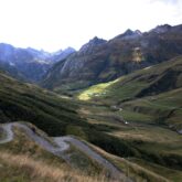 Paysage montagnard avec une route à flanc de montagne et des sommets en fond