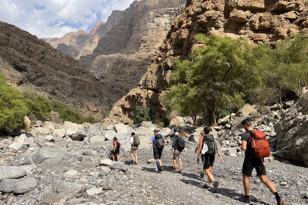 Groupe de randonneurs avec leur guide sur un sentier de pierre à travers les montagnes d'Oman