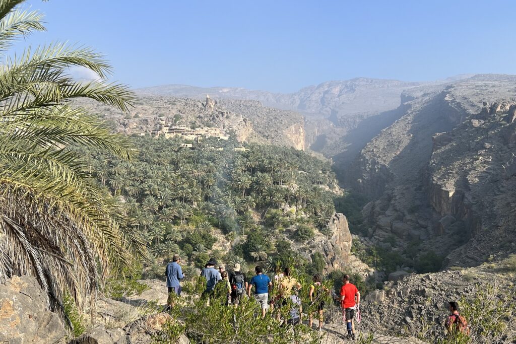 Groupe de randonneurs avec leur guide sur un sentier de montagne face à une vallée avec beaucoup de végétation