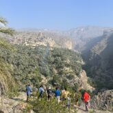Groupe de randonneurs avec leur guide sur un sentier de montagne face à une vallée avec beaucoup de végétation