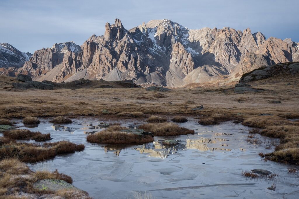 Paysage dans les Alpes avec des sommets aux couleurs grises en fond et un lac de montagne au premier plan