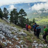 Groupe de randonneurs sur un sentier de randonnée avec une vallée en contrebas sur la droite et des rochers sur la gauche