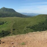Paysage montagnard d'Auvergne avec des sommets et de l'herbe très verte sur les flancs de la montagne
