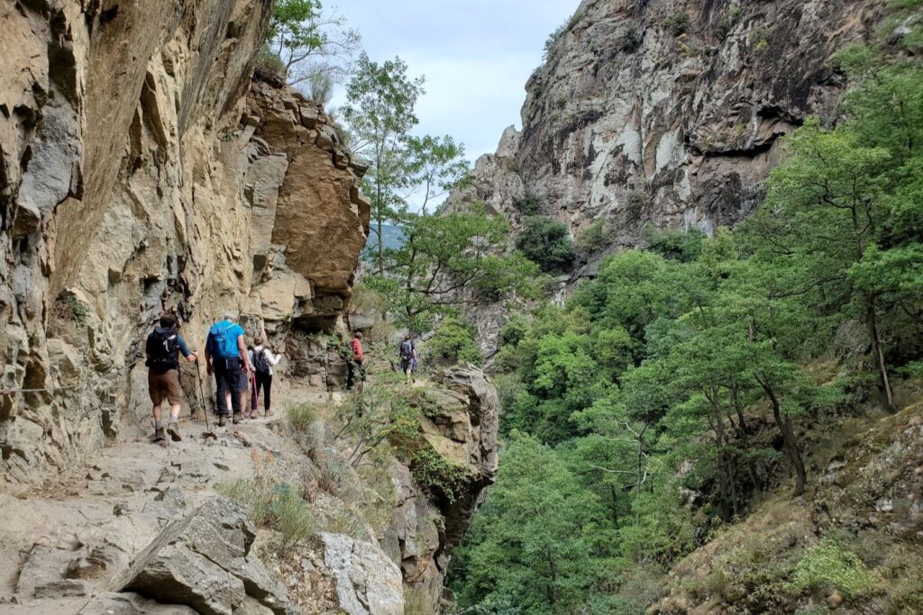 Groupe de randonneurs qui marchent sur un sentier au bord d'une petite falaise sur le GR10