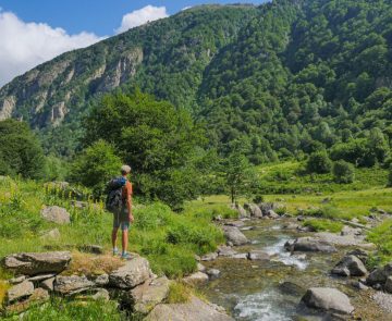 GR10-etape-5-randonnee-liberte Randonneur au bord d'un cours d'eau qui regarde la montagne autour