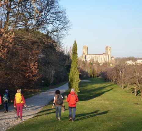 Randonneurs marchant sur un chemin en direction d'un village dans le Gers.