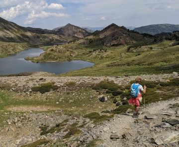 Groupe de randonneurs sur un sentier avec leur guide, paysage de montagne avec un lac en contrebas