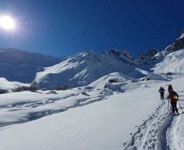 Groupe de randonneurs sur un sentier de randonnée avec en fond des sommets couverts de neige.