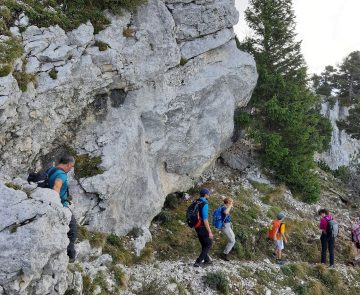 Groupe de randonneurs sur un sentier dans le Vercors encadré de roches et d'arbres