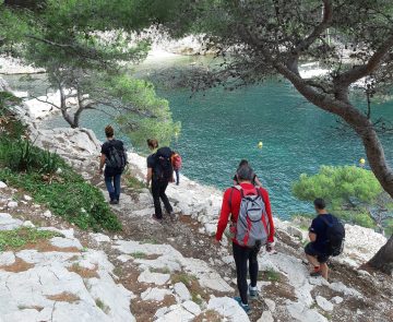 Groupe de randonneurs avec leur guide sur un sentier de randonnée, avec en contrebas la mer