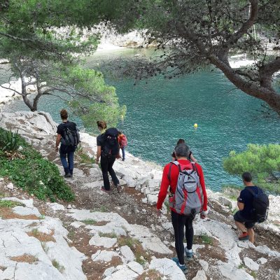 Groupe de randonneurs avec leur guide sur un sentier de randonnée, avec en contrebas la mer