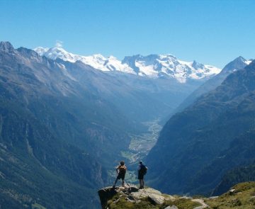 Deux randonneurs sur un rocher face aux différents sommets, face à eux, sur la haute route de Chamonix-Zermatt