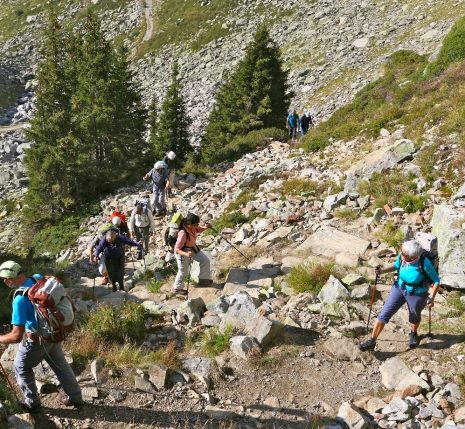 Groupe de randonneurs sur un sentier de randonnée avec beaucoup de cailloux en train de monter avec leur guide lors du tour du mont Blanc sud