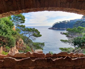 Paysage observé à travers une fenêtre de pierre en Costa Brava, avec un paysage idyllique avec des pins parasols et la mer aux couleurs magnifiques