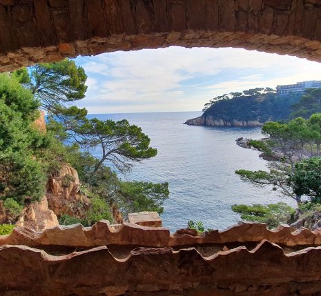 costa-brava-nouvel-an-rando Paysage observé à travers une fenêtre de pierre en Costa Brava, avec un paysage idyllique avec des pins parasols et la mer aux couleurs magnifiques