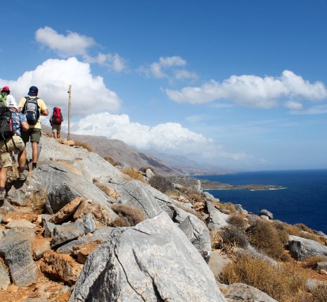 Groupe de randonneurs sur un sentier de montagne avec la mer en contrebas en Crète