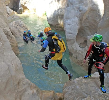 groupe de personnes en train de faire du canyoning avec leur guide, qui sautent dans l'eau dans un canyon en sierra de guara