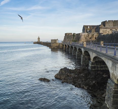 Paysage jersey, une des îles au large de la Bretagne avec un pont sur la droite et des habitations et l'océan sur la gauche