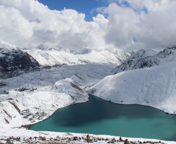 Paysage montagnard au Népal avec un lac bleu au milieu des montagnes enneigées