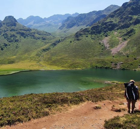 Paysage de montagne avec un sentier sur lequel un groupe de marcheurs avance et un lac sur la gauche