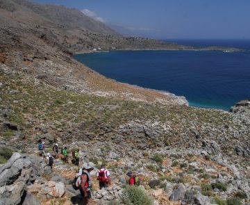 Groupe de randonneurs en Crète sur un sentier à flanc de montagne avec en contrebas la mer