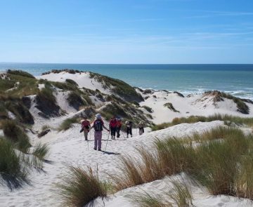 Groupe de randonneurs marchant dans le sable blanc sur une plage de la baie de Somme
